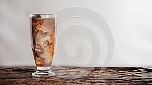 Beverage background of a glass of cold milk coffee on wooden table with white background