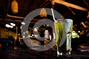 Beverage with ice in glass cup stands on table on background summer cafe.