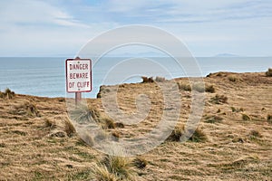 Beware of cliff warning sign, coastal landscape