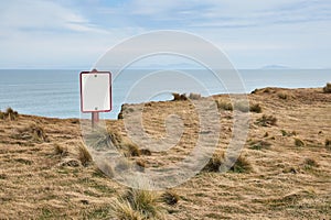 Beware of cliff warning sign, coastal landscape