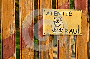 Beware of the dog! Bad furious dangerous dog sign on wooden fence.