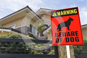 A Beware of Dog Sign in front of a typical 2 story house. Warning to visitors or burglars. Security and protection in a