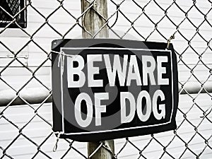 A beware of dog sign on a mesh fence as a safeguard warning of dangerous rottweiler attack if trespassing