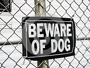 A beware of dog sign on a mesh fence as a safeguard warning of dangerous rottweiler attack if trespassing photo