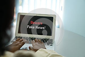 Beware Fake news concept : hands surfing internet on laptop