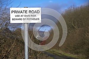 Beware of potholes private road sign in countryside
