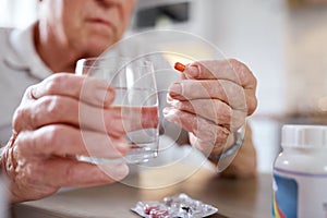 Beware this troubled world, control your intake. Closeup shot of an elderly man taking medication while siting at the
