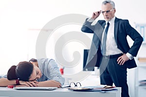 Bewildered chief looking at his employee sleeping at work