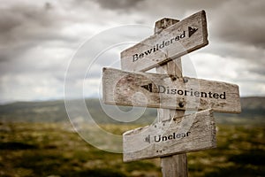 Bewildered, disoriented and unclear text on wooden signpost outdoors in nature.