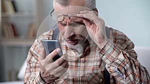 Bewildered old man looking at cellphone, new technology complicated for elderly