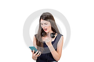 Bewildered young woman with headphones looking shocked, mouth open at her smartphone, isolated on white background