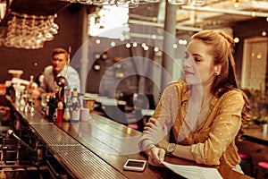 Bewitching lady with red hair sitting at the bar counter photo