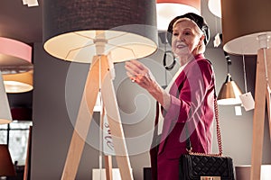 Bewitching stylish elderly female designer choosing new interior lamp photo