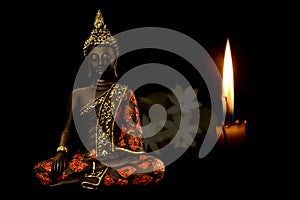 Bhagwan Goutam Buddha in candle light and white flowers in background, pioneer or founder of Buddhism