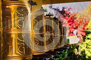 Bhuddhist prayer wheel golden inscribed with a sanskrit prayer and creamy bokeh .