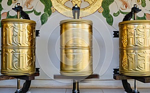 Bhuddhist prayer wheel golden inscribed with a sanskrit prayer and creamy bokeh .