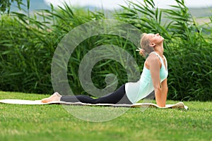 Bhujangasana cobra pose by woman on green grass in the park