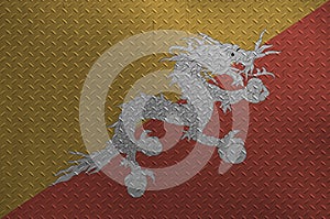 Bhutan flag depicted in paint colors on old brushed metal plate or wall closeup. Textured banner on rough background