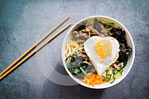 Bi bim bap with beef and chopsticks on concrete background. Traditional Korean food. Top view