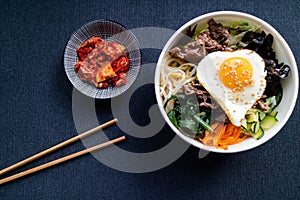 Bi bim bap with beef and kimchi on dark background. Korean cuisine. Top view