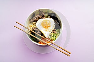 Bi bim bap with rice, beef, wakame, egg, cucumber, carrot and soy sprouts on pink background. Korean cuisine. Top view