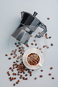 Bialetti moka pot. Coffee maker and coffee beans in mug on gray background. Top view