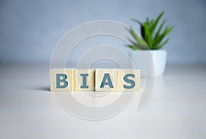 Bias - word from wooden blocks with letters, personal opinions prejudice bias concept, random letters around, white background