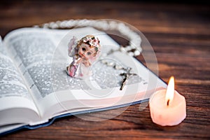 The Bible, angel and candle on wooden background. Christian faith. Christmas Day