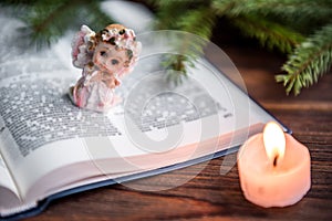 The Bible, angel and candle on wooden background. Christian faith. Christmas Day