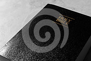 Bible with black cover on light gray table, closeup. Christian religious book