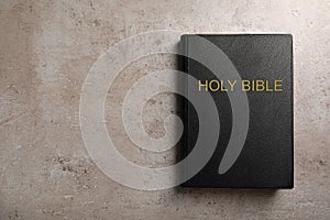 Bible with black cover on light grey table, top view. Space for text