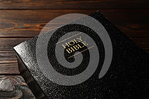 Bible with black cover on wooden table, closeup. Christian religious book