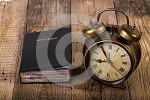 Bible with clock on wood