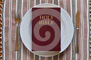 Bible on a dinner plate with silverware