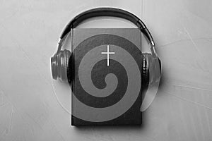 Bible and headphones on light grey background, top view. Religious audiobook