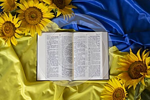Bible Holy Writ and sunflowers on background of flag Ukraine