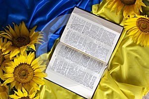 Bible Holy Writ and sunflowers on background of flag Ukraine