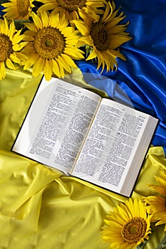 Bible Holy Writ and sunflowers on background of flag Ukraine