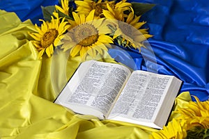 Bible Holy Writ and sunflowers on background of flag Ukraine