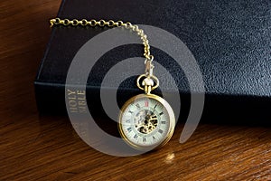 Bible with Old Pocket Watch and Chain on a Wooden Table Top