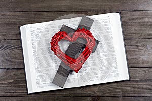 Bible open. Cross, crucifixion of Jesus. Red heart. Love concept. On a wooden table.