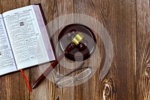 Bible open for study on a wooden table with judge gavel eyeglasses