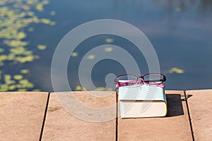 Bible and purple eyeglasses beside the pool