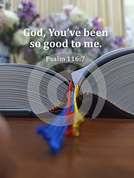 Bible quote - God, You\'ve been so good to me. Psalm 116:7. With bible book on the wooden table and blur flowers background.