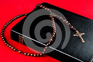 Bible and Rosary with Crucifix on a Red Background