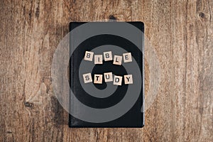 Bible Study in block letters on a bible on a wooden table. Top view flat lay