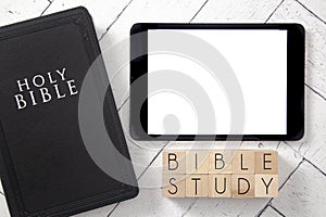 Bible Study in Block Letters on a White Wooden Table with a Black Bible and Tablet