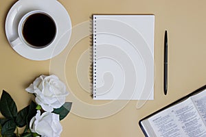 Bible study concept with white roses, notebook, and black coffee over the brown background.