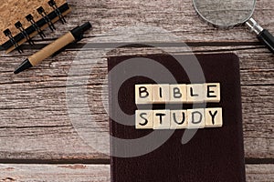 Bible study text written on wooden cubes, Christian holy book, notebook, magnifying glass, and pen on wooden background