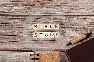 Bible study words on wooden cubes, notebook, Holy Bible Book, and pen on rustic background, top view